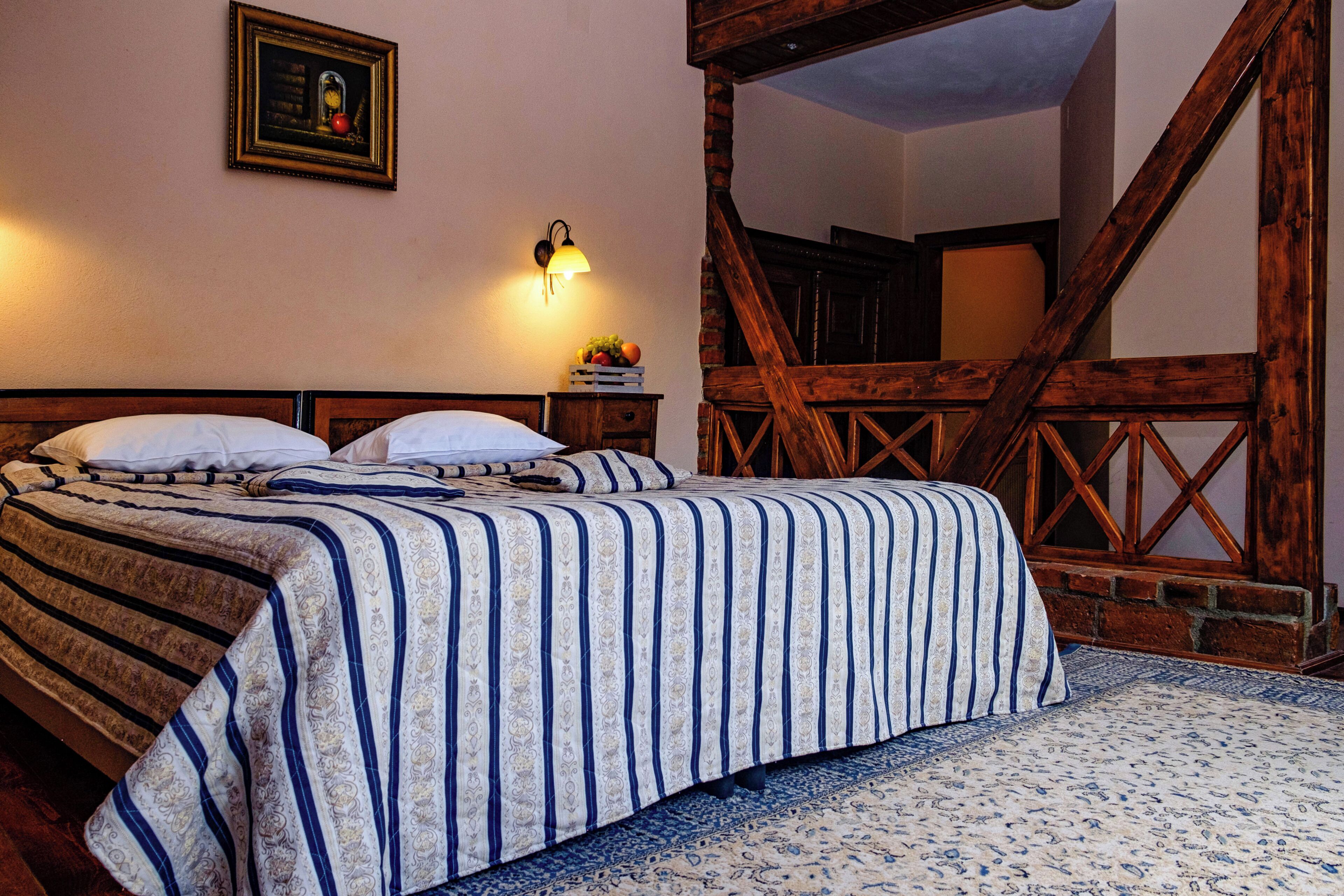 Una cama doble con ropa de cama a rayas, una mesita de noche con una lámpara y un cuadro en la pared.