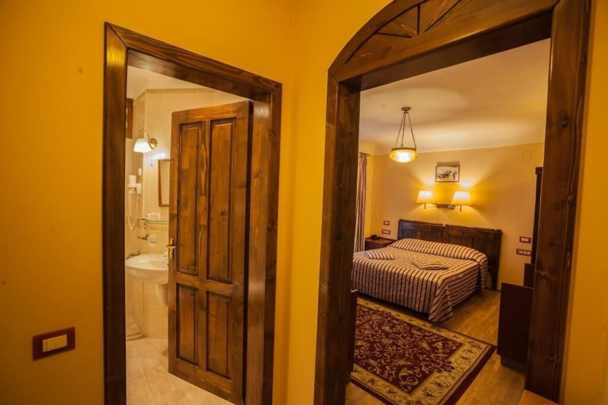 A bedroom with a bed, bedside lamps, and a rug.