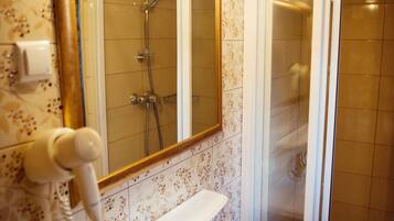Un baño con un lavamanos blanco, un espejo con marco dorado y zona de ducha.