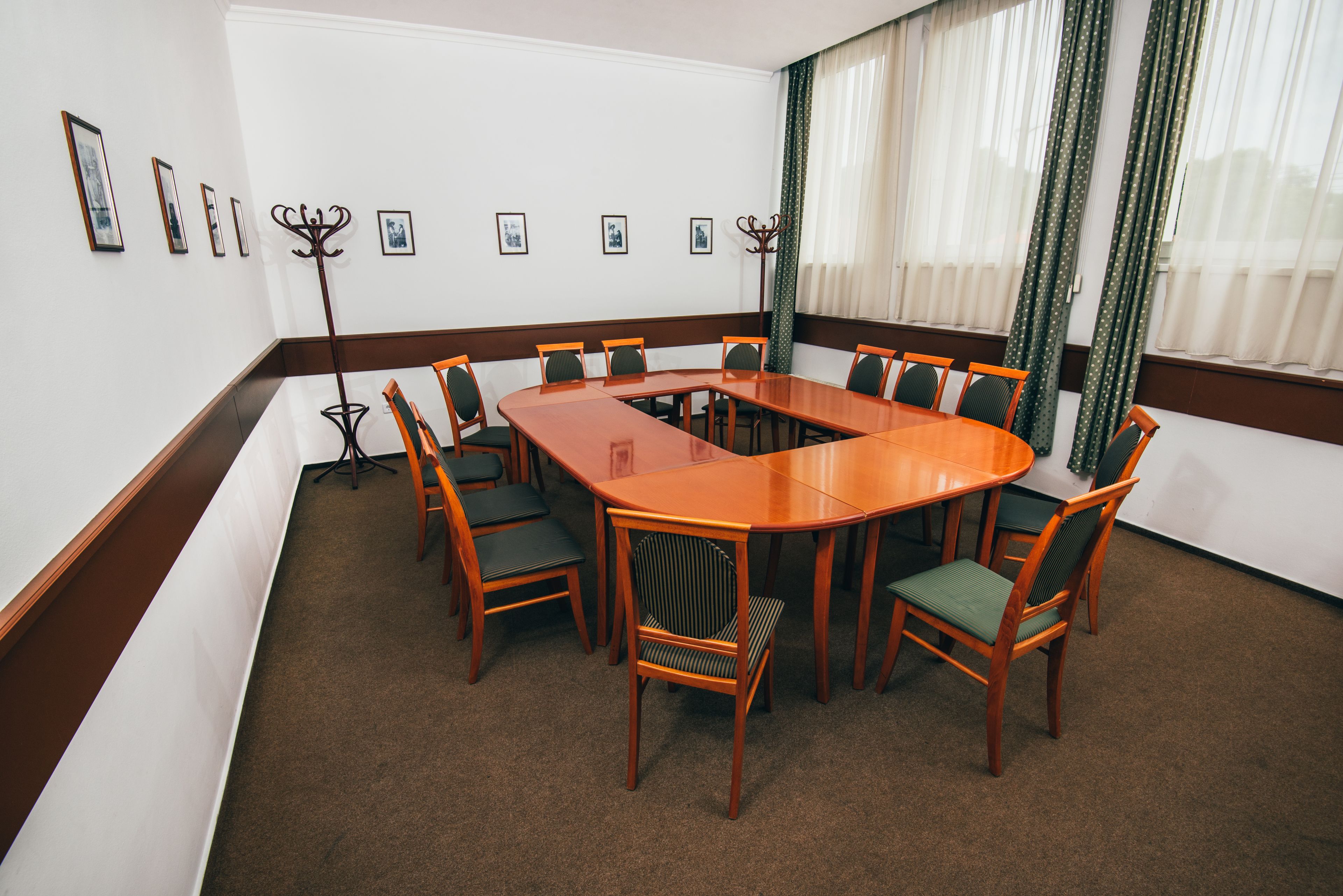 A conference room with a large oval table, six chairs, and a coat rack.