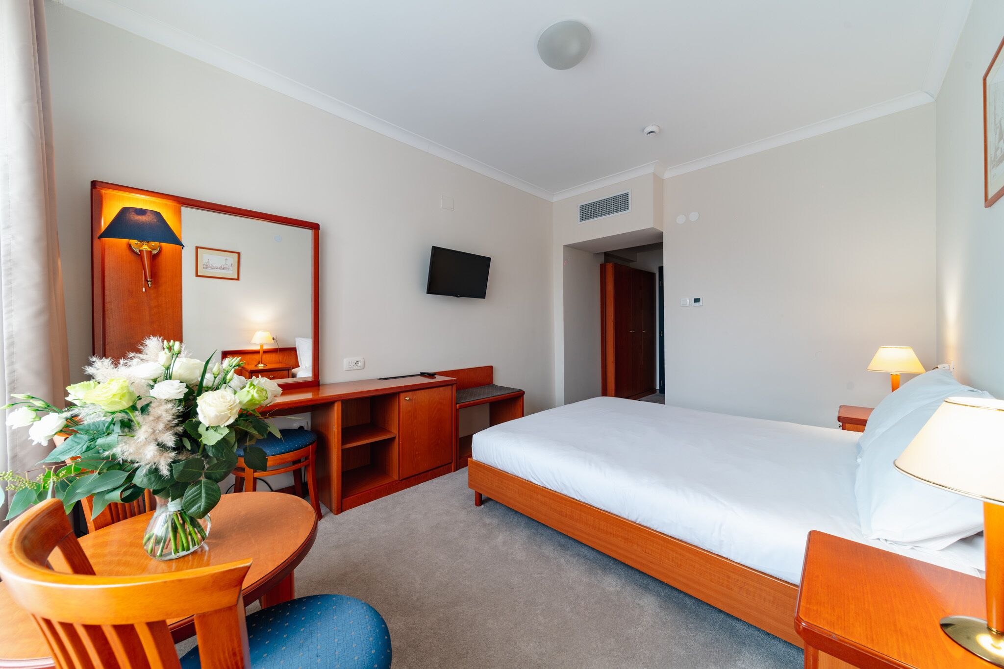 Ein Hotelzimmer mit Bett, Schreibtisch, Stuhl und einem Fernseher an der Wand.