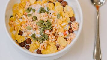 A bowl of cereal with milk and seeds, a plate with sliced fruit, and a glass of orange juice.
