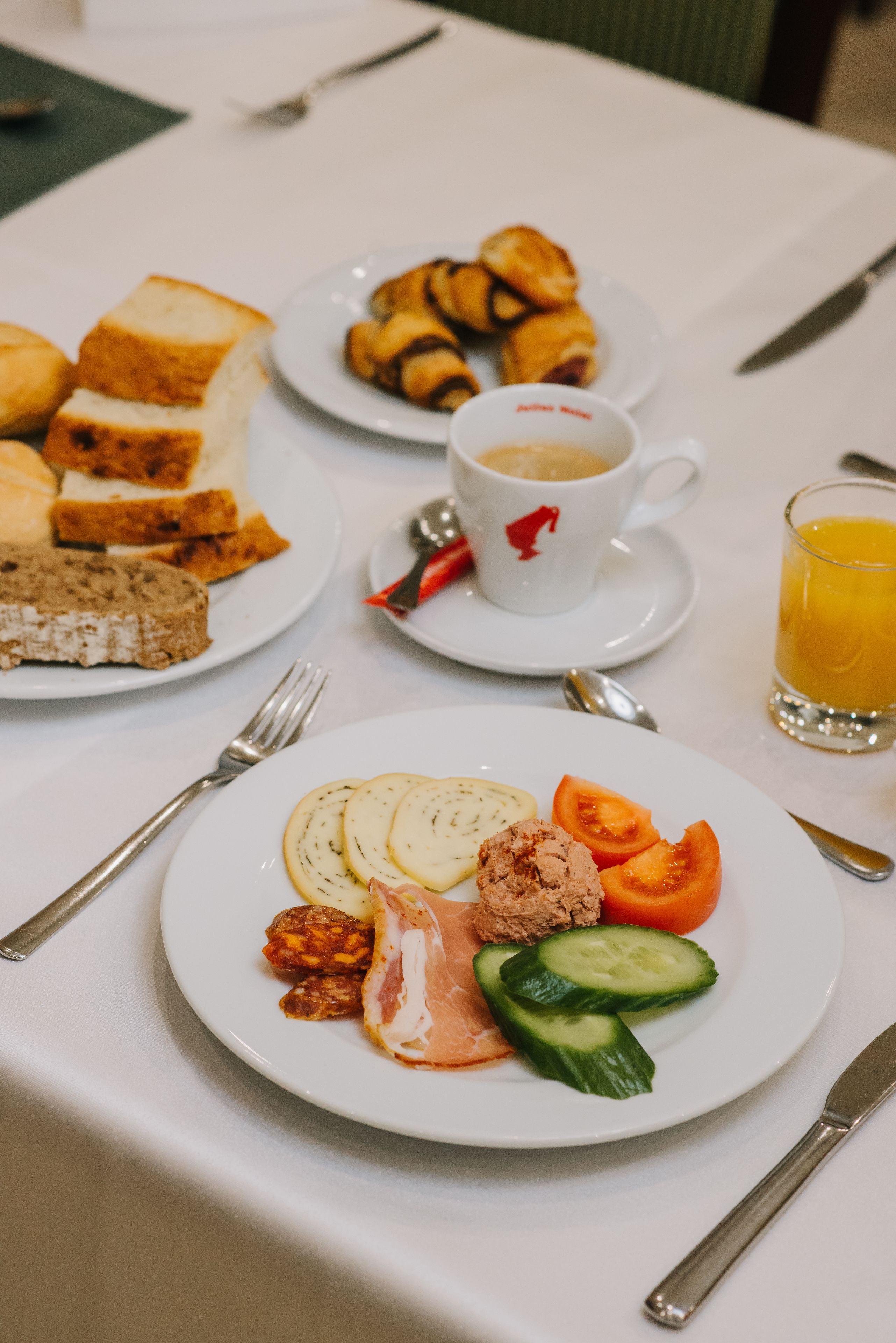 A breakfast setting with plates of food, a cup of coffee, and a glass of orange juice.