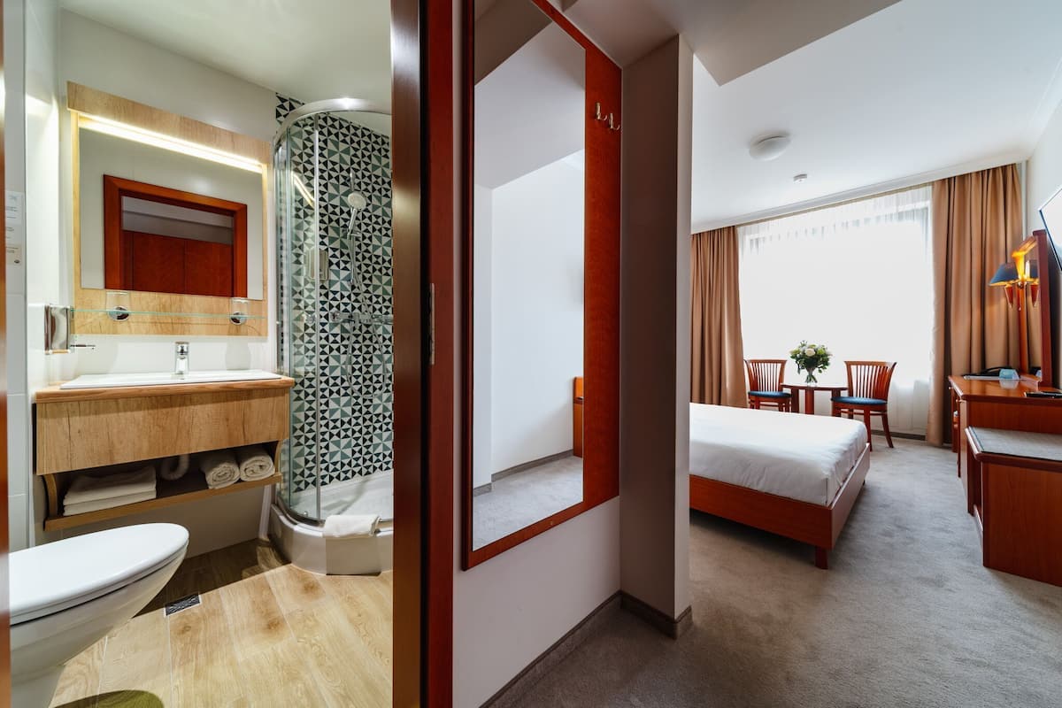 Ein Hotelzimmer mit Bad, Dusche, Bett, Schreibtisch und Stuhl.
