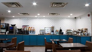 Ein Restaurant mit blauen Schränken, einer gefliesten Spritzschutzwand und mehreren Tischen und Stühlen.