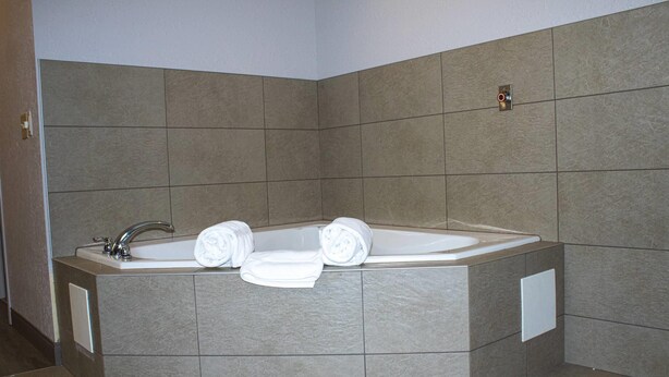 A modern bathroom with a freestanding bathtub, a built-in sink, and a towel rack. - Country Inn & Suites by Radisson, Carlisle, PA (Carlisle)