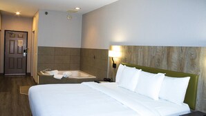 Ein Hotelzimmer mit einem großen Bett, einem Badezimmer mit einer Badewanne und einer Tür mit einem Schild.