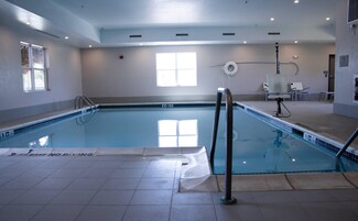 Una piscina interior con agua cristalina, suelo de baldosas y una escalera de acceso.