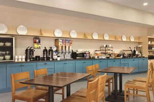 Una cocina moderna con armarios azules, sillas de madera y una estación de café.