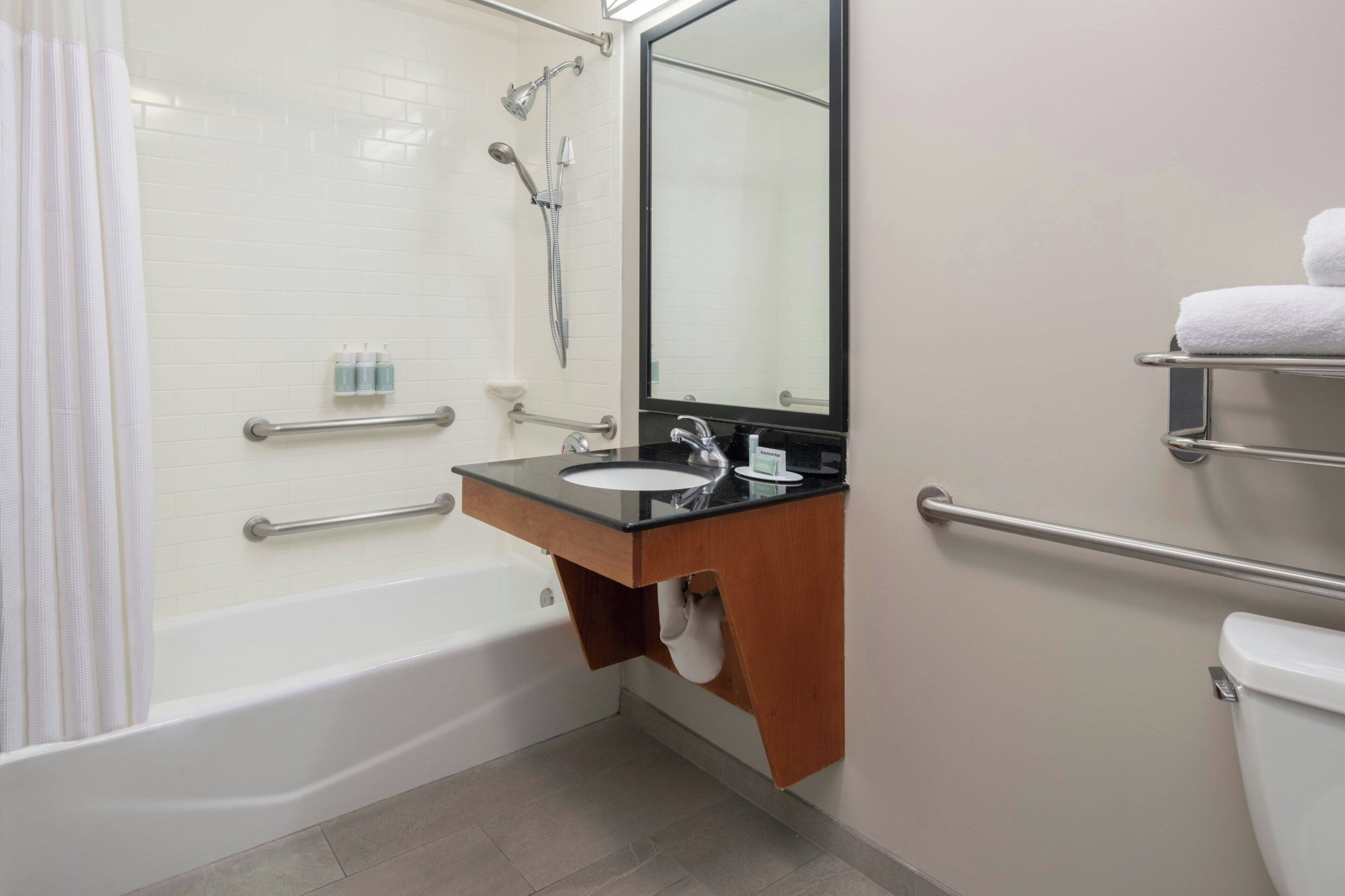 Un baño con bañera, lavamanos con espejo y retrete.