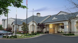 A hotel with a classic architectural style, featuring a prominent entrance with a covered walkway and a flagpole. - Homewood Suites by Hilton Fort Smith (Fort Smith)