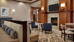 A hotel lobby with a fireplace, seating area, and a television mounted on the wall. - Homewood Suites by Hilton Fort Smith (Fort Smith)