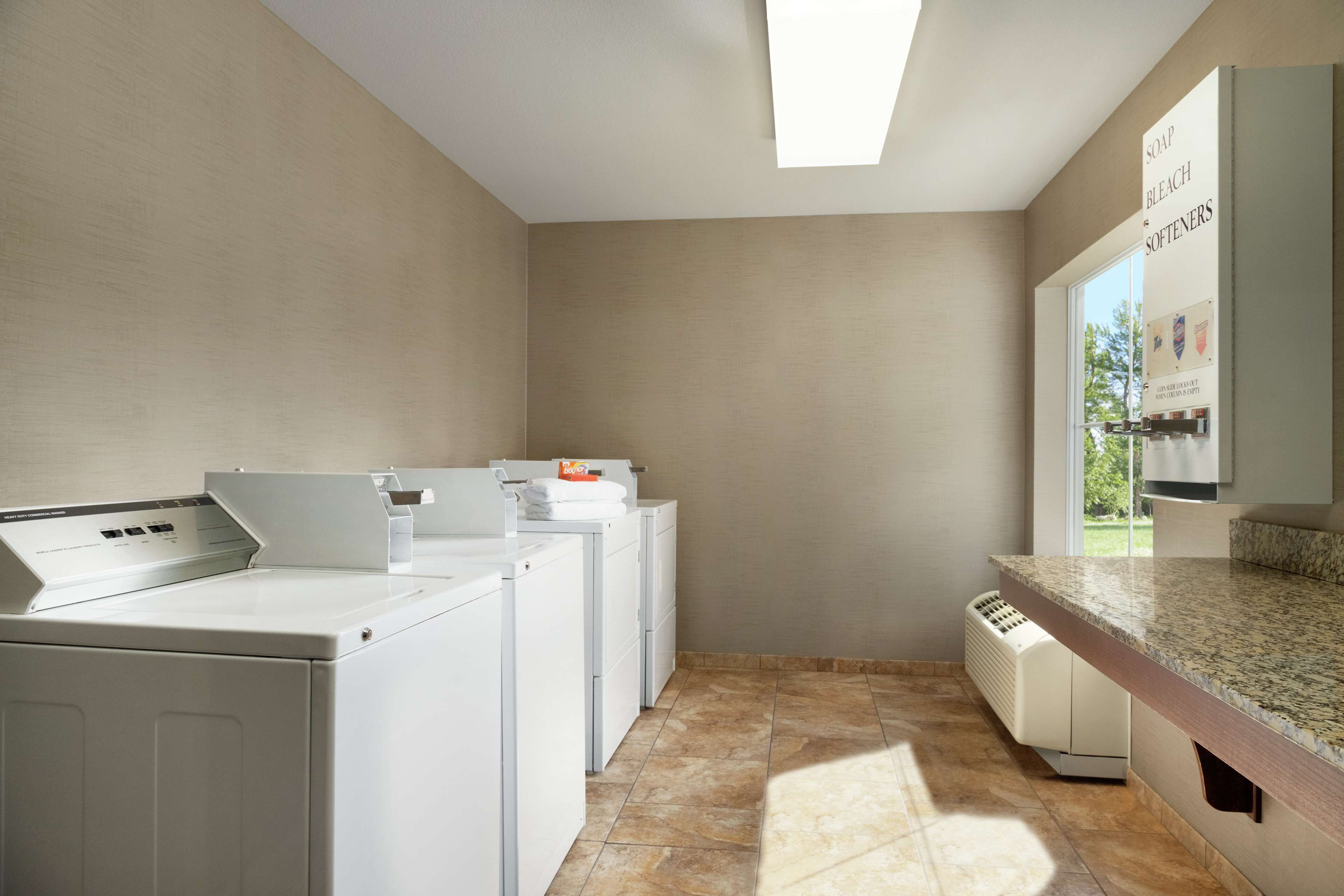 A laundry room with a washing machine, dryer, and a countertop with a soap dispenser.