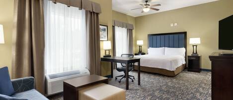 Ein Hotelzimmer mit Bett, Schreibtisch, Sessel, Sofa und Fernseher.