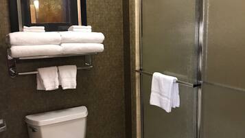 A bathroom with a toilet, a glass shower enclosure, and a towel rack with folded towels.