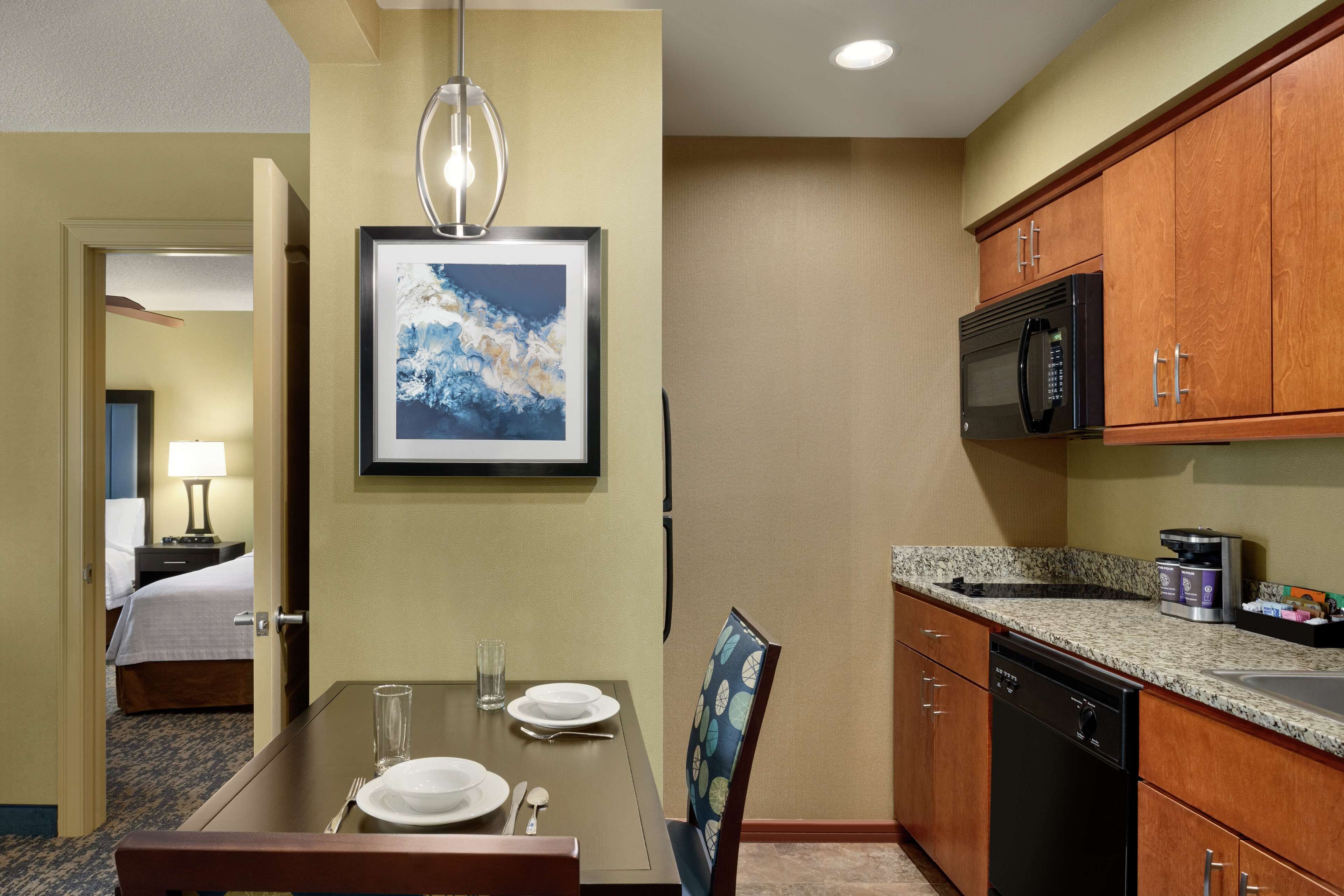 Una habitación de hotel con comedor, cama, microondas y lavavajillas.