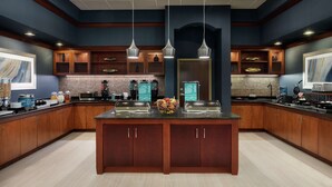 A modern kitchen with wooden cabinets, a central island, and pendant lighting. - Homewood Suites by Hilton Fort Smith (Fort Smith)