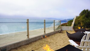 A beachside patio with a fire, lounge chairs, and a view of the ocean. - The Coho Oceanfront Lodge (Lincoln City)