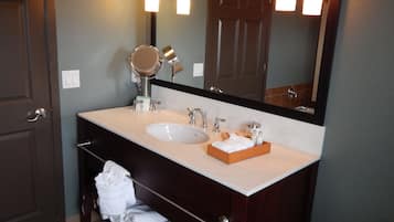 Un baño con lavamanos doble, espejo y toallero.