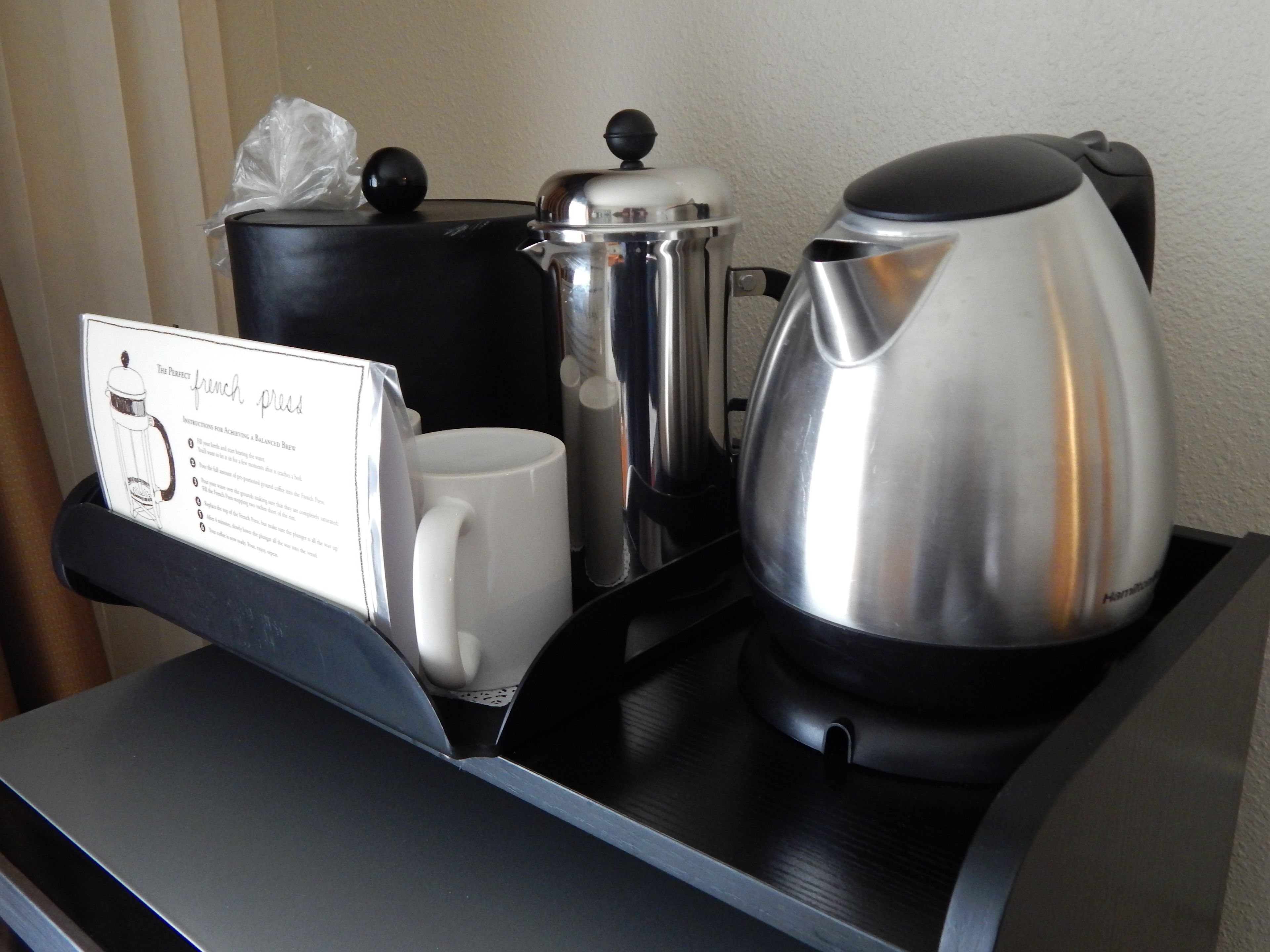 A coffee station with a French press, a mug, a kettle, and a pot.