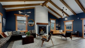 A modern living room with a fireplace, wooden beams, and a large window. - The Coho Oceanfront Lodge (Lincoln City)