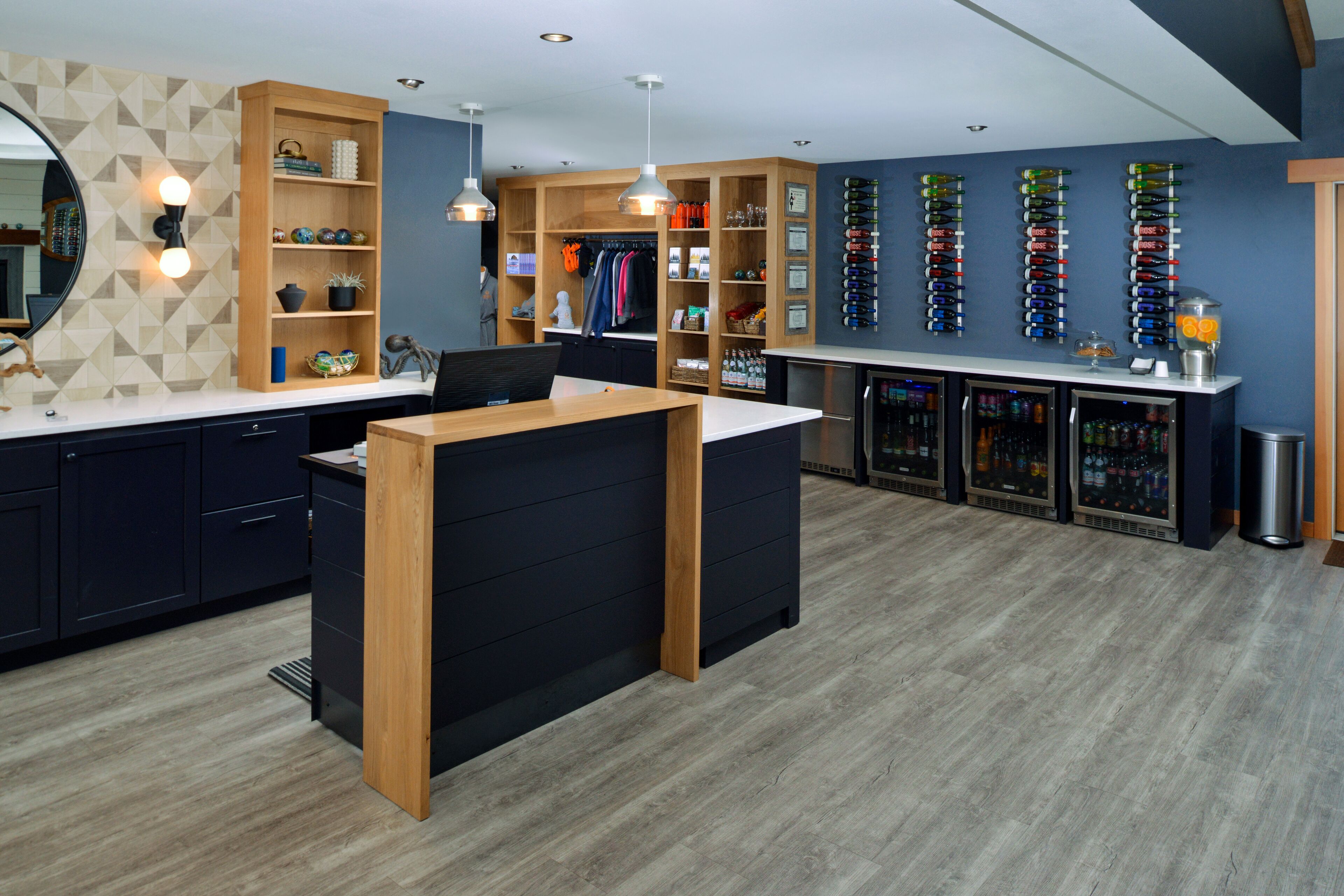 A modern bar area with a wooden counter, shelves with bottles, and a wine rack.