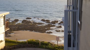 Vista d'una platja rocosa amb un camí corbat que condueix a una zona de seients, amb vista a l'oceà.