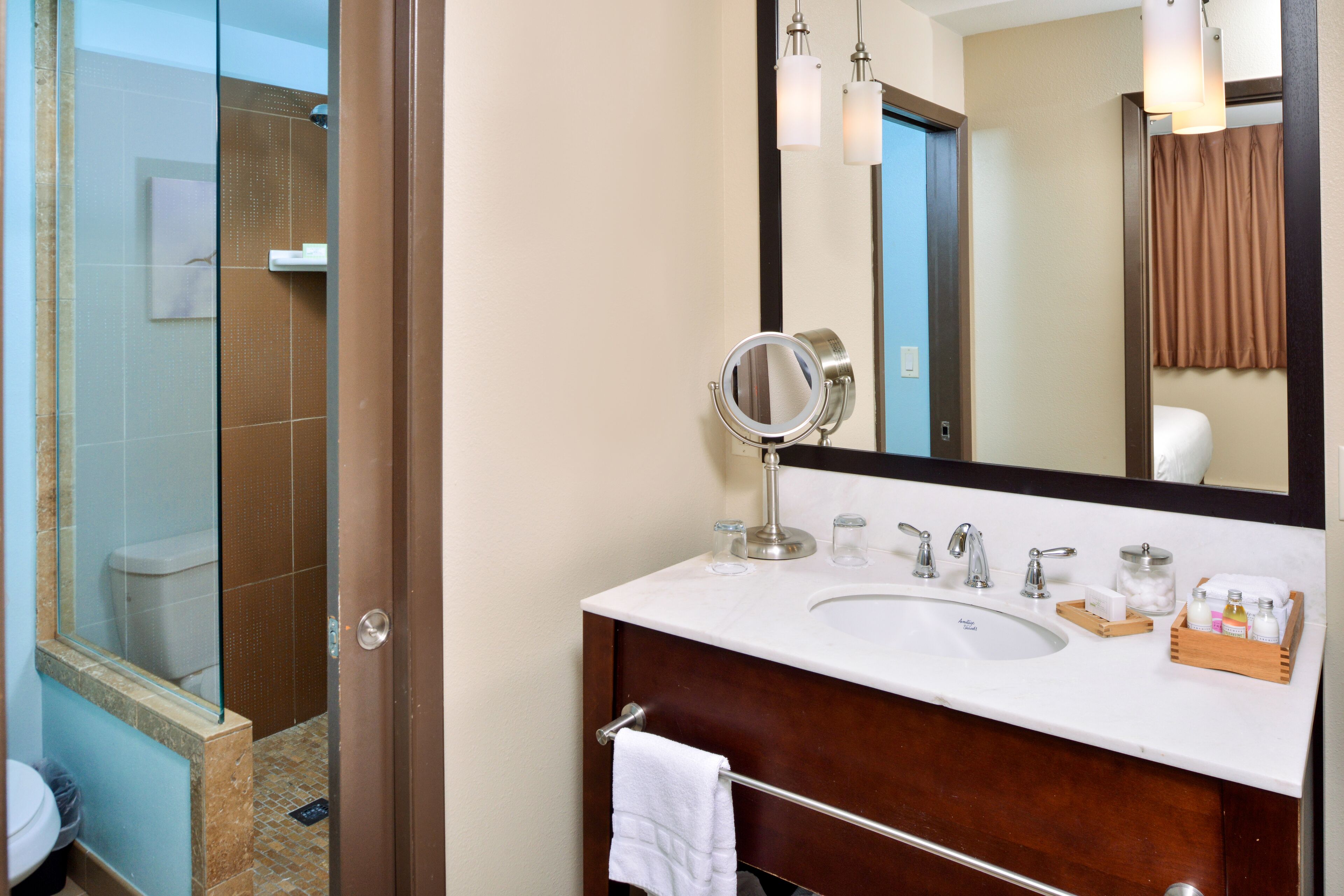 A bathroom with a glass shower enclosure, a sink with a mirror, and a towel rack.