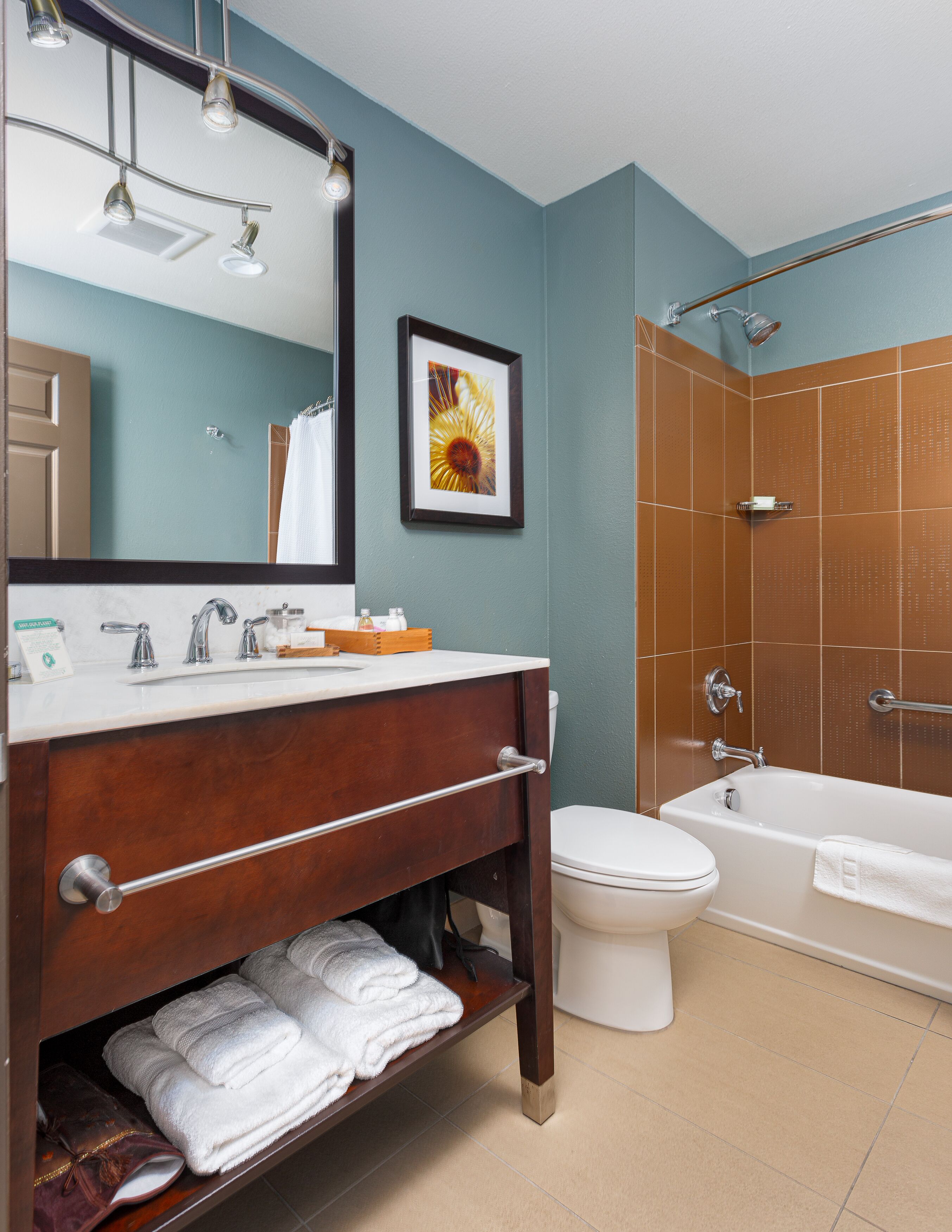 A bathroom with a wooden vanity, a white toilet, a bathtub, and a shower.