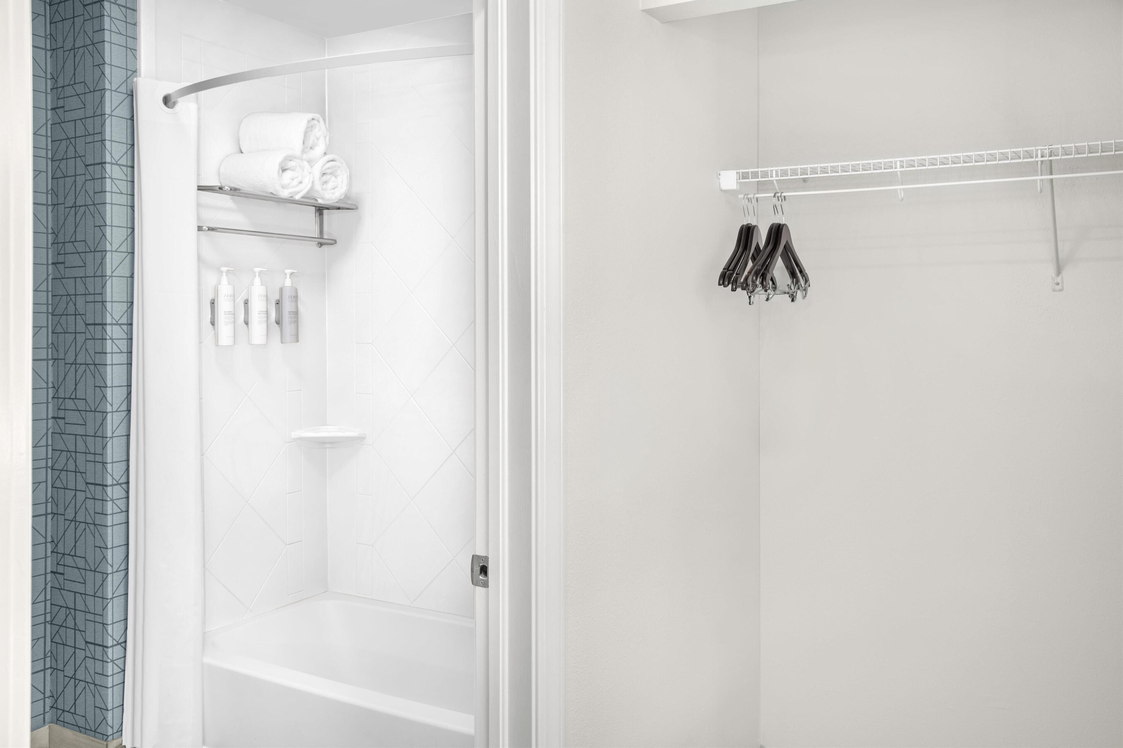 Un baño moderno con ducha, toallero y estante con artículos de aseo.