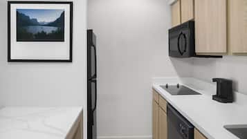 A modern kitchen with a built-in dishwasher, a microwave, and a coffee machine.