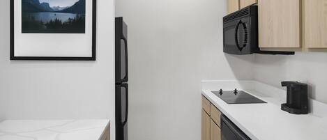 Una cocina moderna con lavavajillas incorporado, microondas y cafetera.