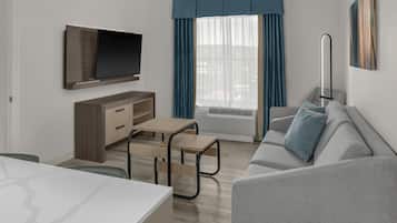 A modern living room with a flat-screen TV, a sofa, a coffee table, a TV stand, and a window with curtains.