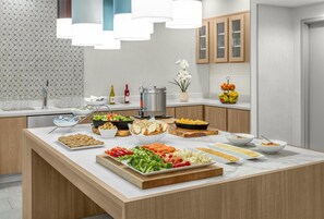 A modern kitchen with a marble countertop, various food items, and a decorative light fixture.