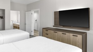 A hotel room with two beds, a wooden dresser, a flat-screen TV, and a bathroom visible through an open door. - Homewood Suites by Hilton Fayetteville (Fayetteville)