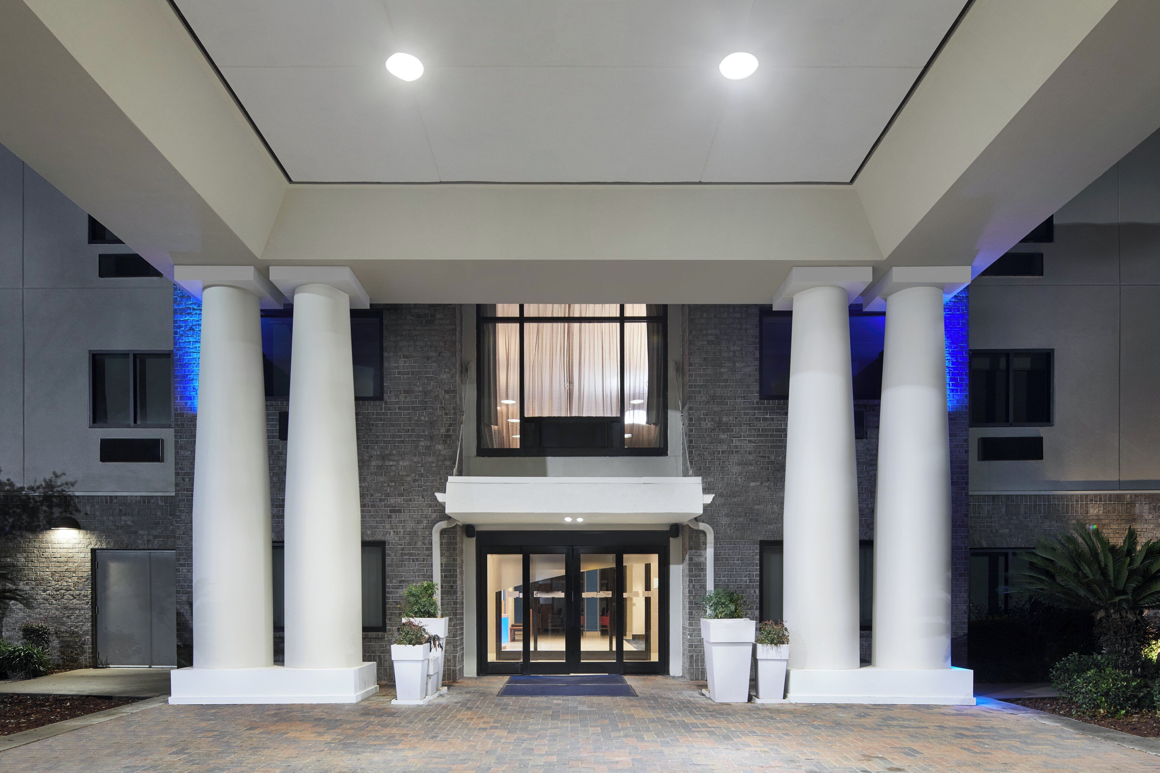 A hotel entrance with a modern design, featuring large columns, a brick facade, and a welcoming entrance.