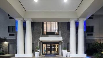 A hotel entrance with a modern design, featuring large columns, a brick facade, and a welcoming entrance.