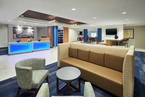 A hotel lobby with a reception desk, seating area, and a television. - Holiday Inn Express Pensacola West - Navy Base by IHG (Pensacola)