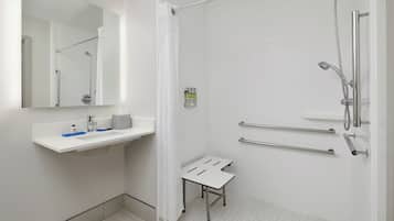 A modern bathroom with a shower, a sink with a mirror, and a small stool.