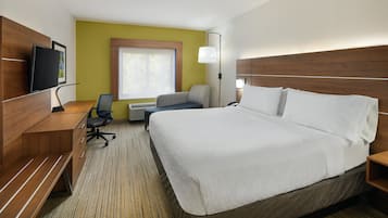 Habitación de hotel con una cama grande, un escritorio con silla, televisión y ventana con persianas.