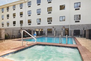 A hotel with a swimming pool, outdoor seating, and a brick wall. - Holiday Inn Express Pensacola West - Navy Base by IHG (Pensacola)