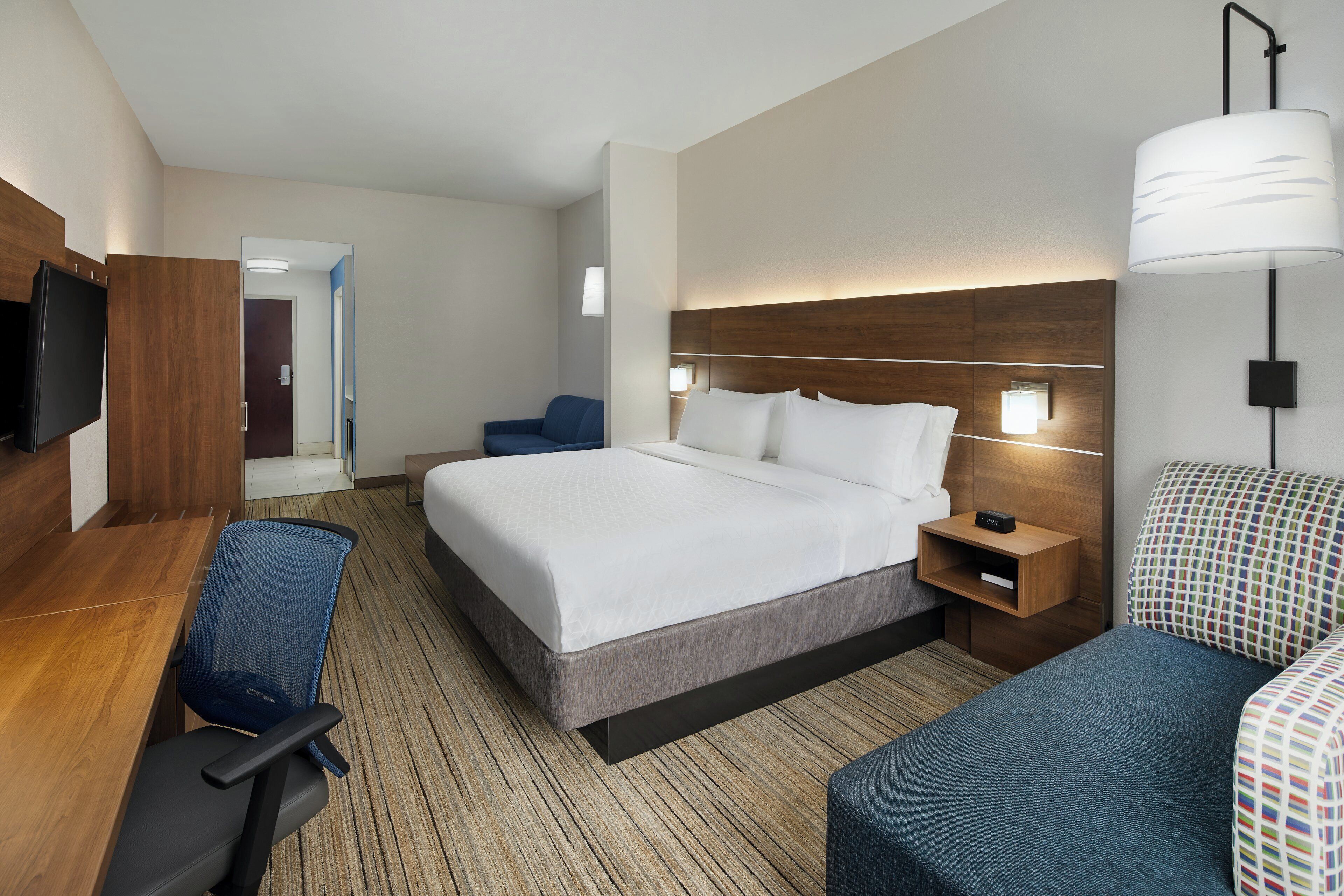 Een hotelkamer met een bed, nachtkastjes, een bureau, een stoel en een televisie.