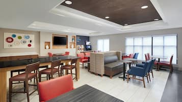 Un moderno hall de hotel con bar, zona de estar y estación de café.
