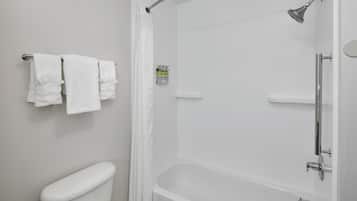 A bathroom with a toilet, a shower with a glass door, and a towel rack with two towels.