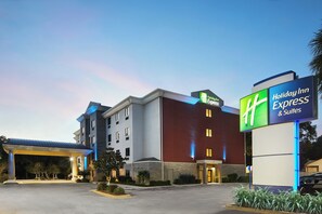 A Holiday Inn Express & Suites hotel with a modern design, featuring a prominent sign, a covered parking area, and a well-maintained landscape. - Holiday Inn Express Pensacola West - Navy Base by IHG (Pensacola)
