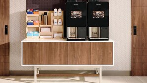 Una cocina moderna con encimera de madera, dos máquinas de café y varios utensilios de cocina.