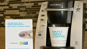A Keurig coffee machine with a cup of coffee and a Holiday Inn Express sign. - Holiday Inn Express Hotel & Suites FRESNO NORTHWEST-HERNDON by IHG (Fresno)