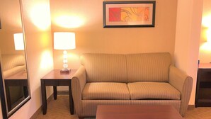 A living room with a sofa, a coffee table, a lamp, and a framed picture on the wall. - Holiday Inn Express Hotel & Suites FRESNO NORTHWEST-HERNDON by IHG (Fresno)