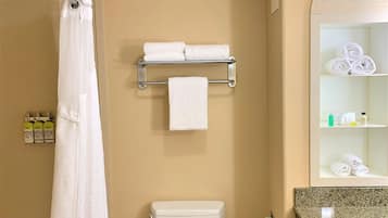 A bathroom with a shower, toilet, towel rack, and shelves with toiletries.