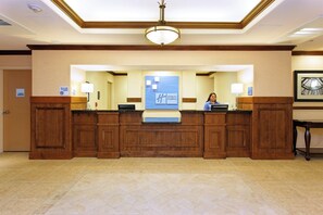 A hotel reception desk with a large blue sign, a clock, and a framed picture on the wall. - Holiday Inn Express Hotel & Suites FRESNO NORTHWEST-HERNDON by IHG (Fresno)